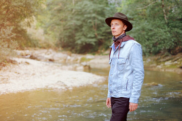 The image of a male traveler researchers at the background of the river in summer.