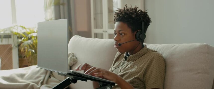 DX Portrait of African American Black kid playing online games on his laptop. Talking to his teammates via headset. Shot with 2x anamorphic lens