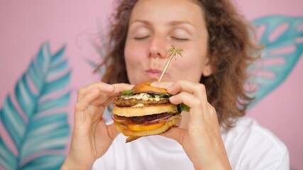 Close up of hungry Caucasian woman taking bite of double-decker vegan burger 