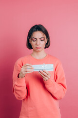 Portrait of upset frustrated girl opening gift box isolated on pink background