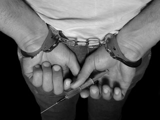 Arrested man holding injection syringe with drug, handcuffs on man,drug dealer loss freedom