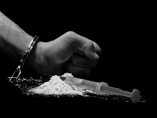 Handcuffed man and cocaine drug powder pile and injection syringe, arrested drug dealer