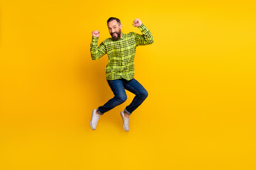 Fototapeta na wymiar Full body photo of excited man happy positive smile jump up celebrate win victory fists hands isolated over yellow color background