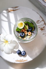 Chia pudding with granola, blueberries, hazelnut on white wooden stand. Top view