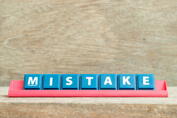 Obraz premium Tile alphabet letter with word mistake in red color rack on wood background