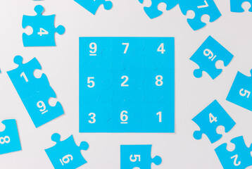 Blue puzzle pieces with numbers on a white background, logo of autism. April 2, Autism World Awareness day. Top view
