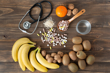 Some nutrients, fruits and medicines to take care of food on a dark wood background. Healthy lifestyle concept.
