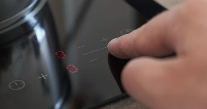 Adjusting temperature on touch panel of induction cooker by pressing plus and minus touch buttons. Modern kitchen appliances, cooktop close up.