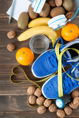 Top view of some natural foods, sneakers and meter tape on a dark wooden background. Concept of health, food and sport.