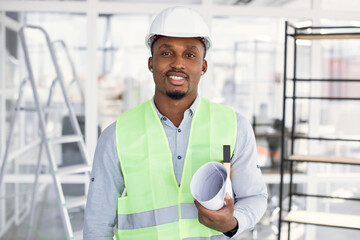 Confident afro-american man in white hardhat standing among repair equipments and looking at camera. Competent arhitect checking working process of construction.