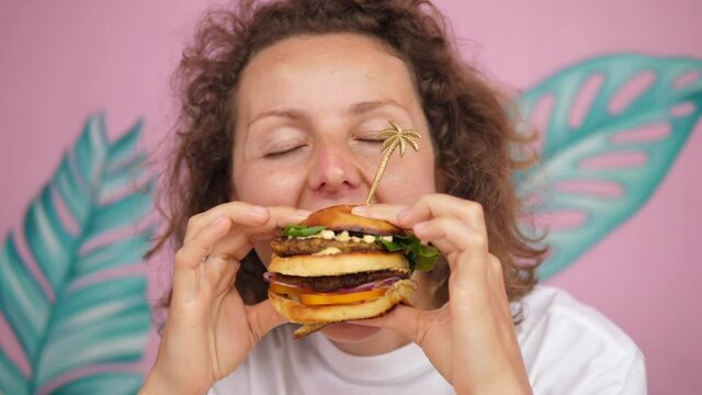 Close up of hungry Caucasian woman taking bite of double-decker vegan burger 