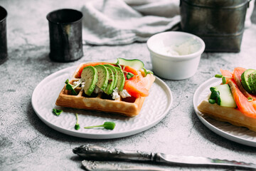 Belgian waffles with salmon, avocado and cream cheese on a white plate. Healthy breakfast at the table