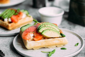 Belgian waffles with salmon, avocado and cream cheese on a white plate. Healthy breakfast at the table