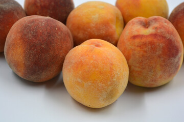 Tasty and useful fresh fruits, ripe red and orange peaches with a terry white skurt are located on a white background. 