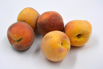 Tasty and useful fresh fruits, ripe red and orange peaches with a terry white skurt are located on a white background. 