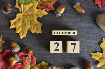 December 27, Cover Date design with Calendar cube decorate with maple leaf and Acorn Oak seed for...