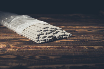 Open pack of welding electrodes on a wooden background. Studio photo in hard light.