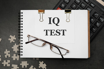 Notebook with words IQ Test, calculator and puzzles on black table, flat lay
