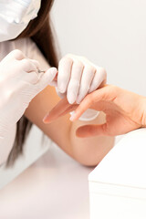 Closeup of manicure master removes nail polish uses an electric nail file in a nail salon