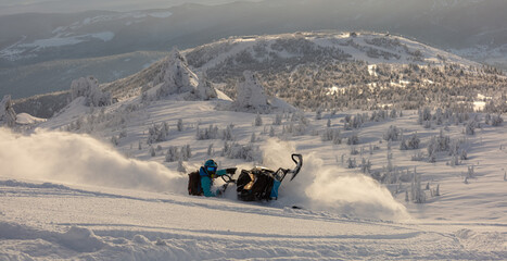 Pro snowmobiler makes a turn and lets a flurry of snow spray from under the caterpillar. sports snowmobile in the mountains. bright skidoo motorbike and suit without brands. Winter fun. panoramic view