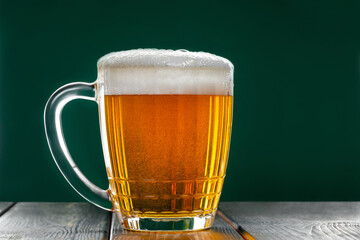 Mug with traditional Irish pale ale on a dark green background. Bubbles in a glass of beer.