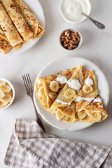 Golden crepes, pancakes with banana and sour cream. Breakfast concept. Maslenitsa. 