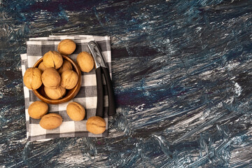 Walnut kernels on a dark table, a whole walnut in a wooden bowl. selective focus