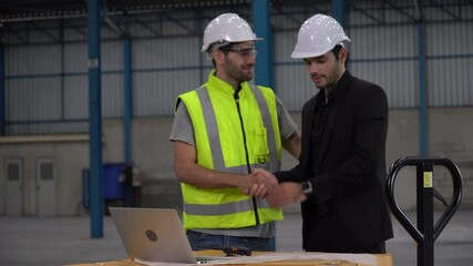 Executive business man handshake with warehouse manager in meeting  with blueprint and laptop at  large warehouse. client visits the factory and inspect with supervisor. Successful business agreement