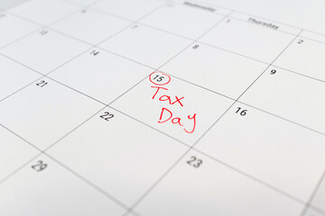 Tax day marked on April 15 calendar with red marker. Deadline for 1040 form return.