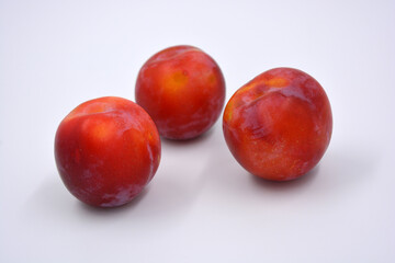 Delicious useful fruits, red, cherry ripe plums located on a white background. 