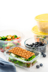 Various food in plastic and glass containers. Salad, bulgur, sandwiches and berries in plastic containers on a white background. Food storage, takeaway. Copy space for text.