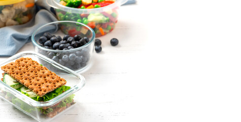 Various food in plastic and glass containers. Salad, bulgur, sandwiches and berries in plastic containers on a white background. Food storage, takeaway. Copy space for text.