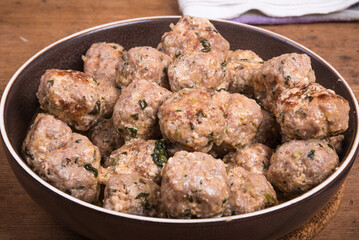 Chicken meatballs with cheese in a creamy sauce in a bowl on a wooden kitchen table, top view, close-up - Swedish cuisine