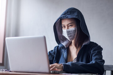 Professional hacker young women Wearing a blue robe with a hood Stealing data from online computer systems By releasing viruses into the system By using laptops and keyboards in older buildings