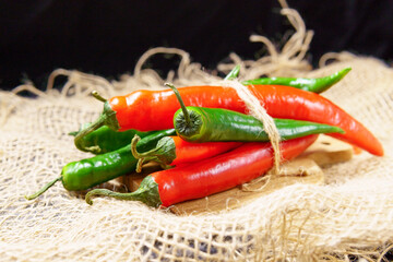Red pepper and green, on dark wooden board, selective focus. Organic food concept.