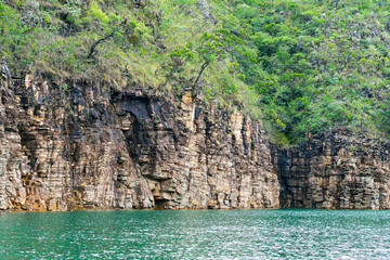 Rock walls of on the shore of the Lake of Furnas, Capit&oacute;lio MG, Brazil. Green water of the lake, sedimentary rocks and the vegetation growing up the rocks. 