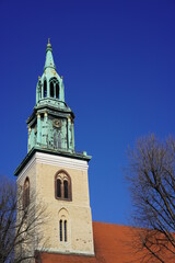 Fototapeta na wymiar Historische, sehenswerte Kirche in Berlin, die St. Marienkirche am Alexanderplatz bei Sonnenschein und blauem Himmel