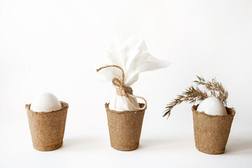Minimalist concept with Easter white eggs in peat pots.