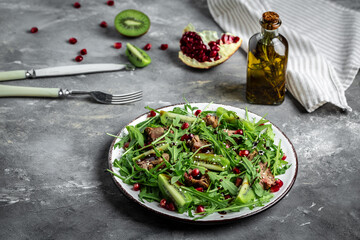Homemade chicken liver Salad. Warm salad with arugula, chicken liver, kiwi and pomegranate. Healthy lunch menu. Diet food. Top view