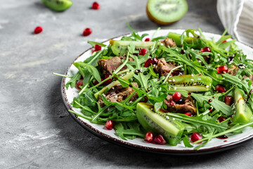Healthy Warm Salad with chicken liver, kiwi and pomegranate, arugula. Top view