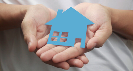 Hands holding paper house, family home  protecting insurance concept