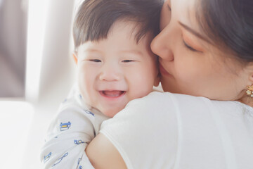 Close up portrait of young beauty Asian mother kissing her newborn baby boy's feet and having fun. Mom playing with her baby. Asia mother's day concept banner