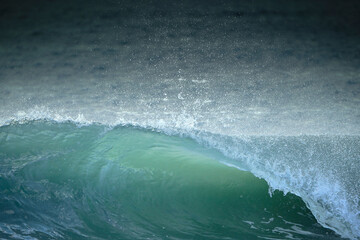 Ola rompiendo con bonitos tonos cien y fondo de mar oscurecido