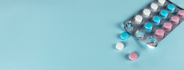 Medicines and pills. Blue, pink and white pills. Multicolored medicines on a pastel blue background.