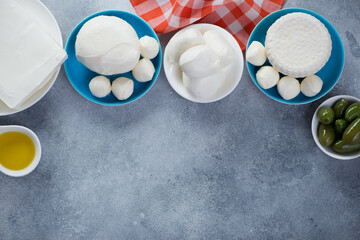 Mozzarella, ricotta and feta cheese on a light-blue stone background, view from above with copy...