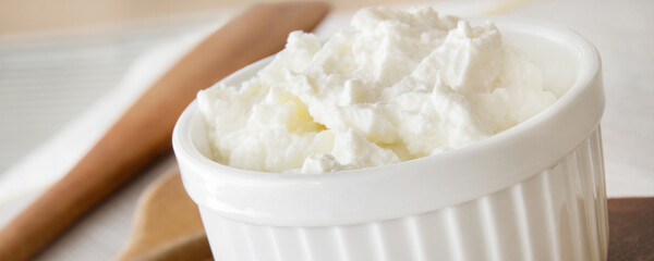 Hüttenkäse mit Kochlöffel in einer Schale close up Banner