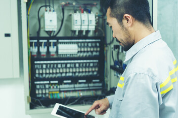 portrait of technician doing the preventive maintenance in the control room. Workers monitoring the status of main electrical industry.