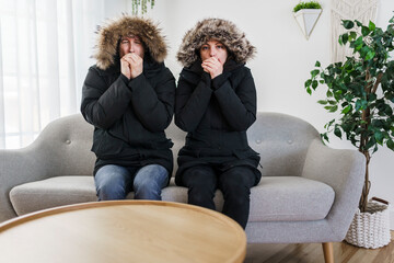 Couple have cold on the sofa at home with winter coat