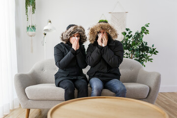 Couple have cold on the sofa at home with winter coat