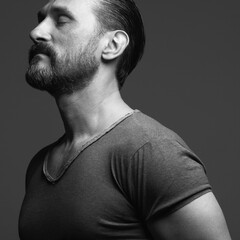 Fabulous at any age. Profile portrait of charismatic muscular 45-year-old man standing over dark...